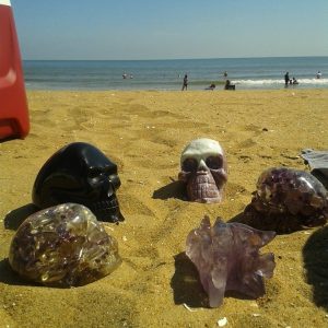 Eine Gruppe Kristallschädel liegt im Sand - spirituelle Reinigung