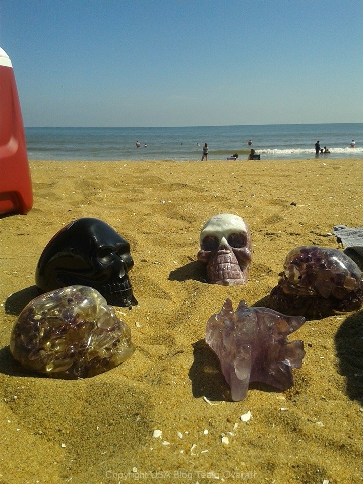 Eine Gruppe Kristallschädel liegt im Sand - spirituelle Reinigung